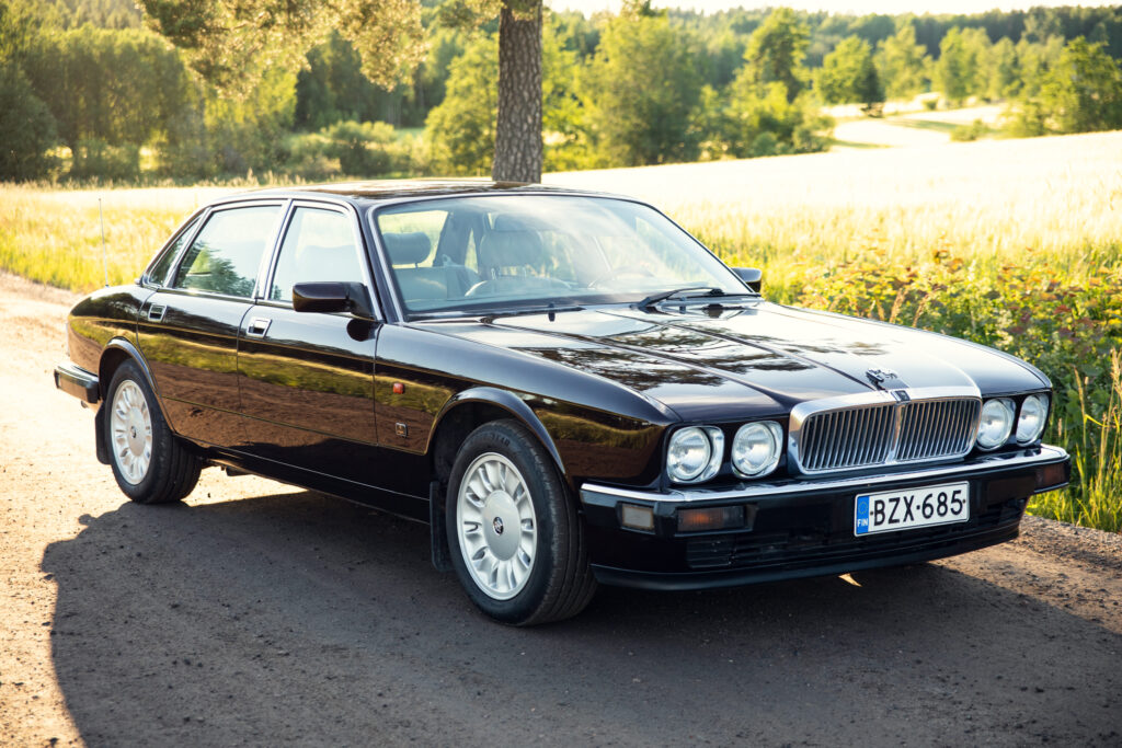 Black classic Jaguar XJ parked on country road