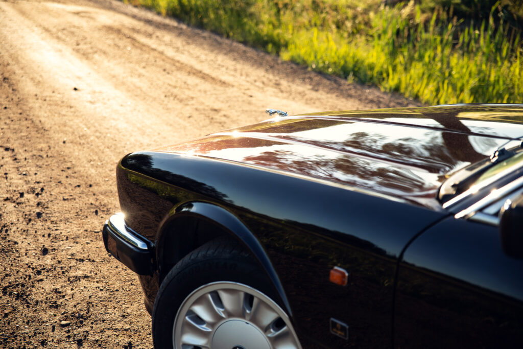 Black luxury car on sunlit dirt road