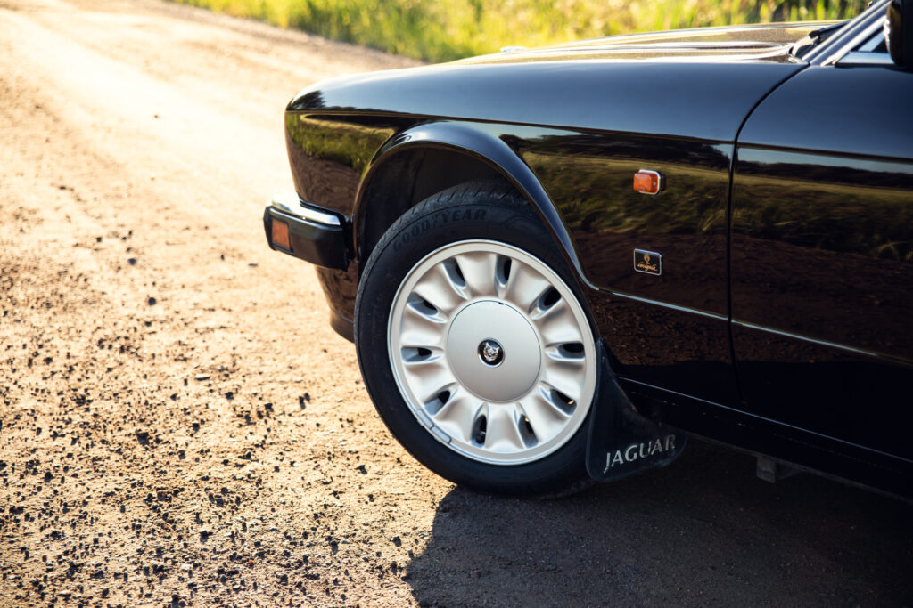 Close-up of black Jaguar car wheel on dirt road