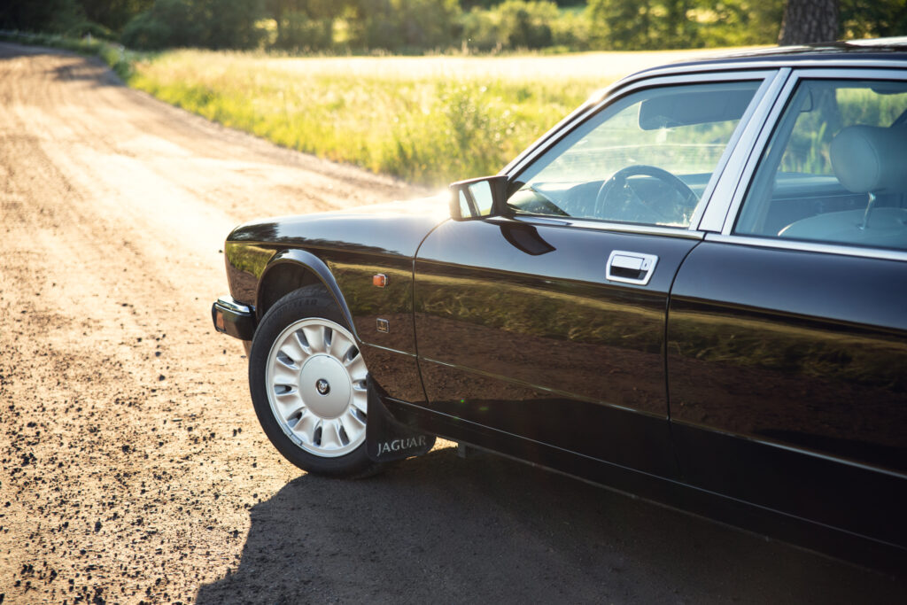 Black Jaguar sedan parked on sunny dirt road