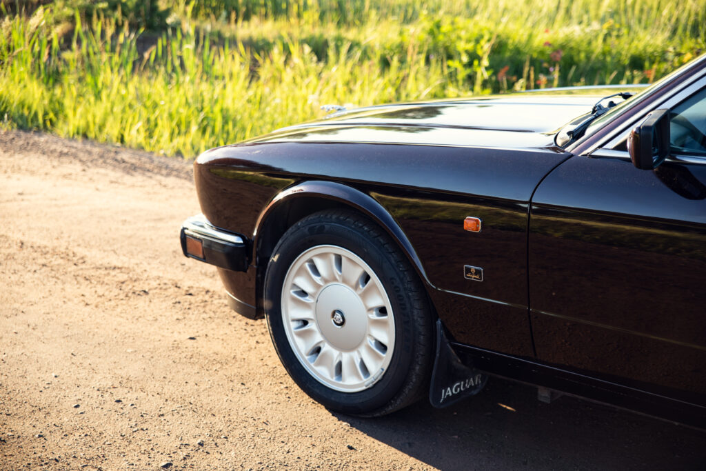 Close-up of vintage Jaguar parked on dirt road