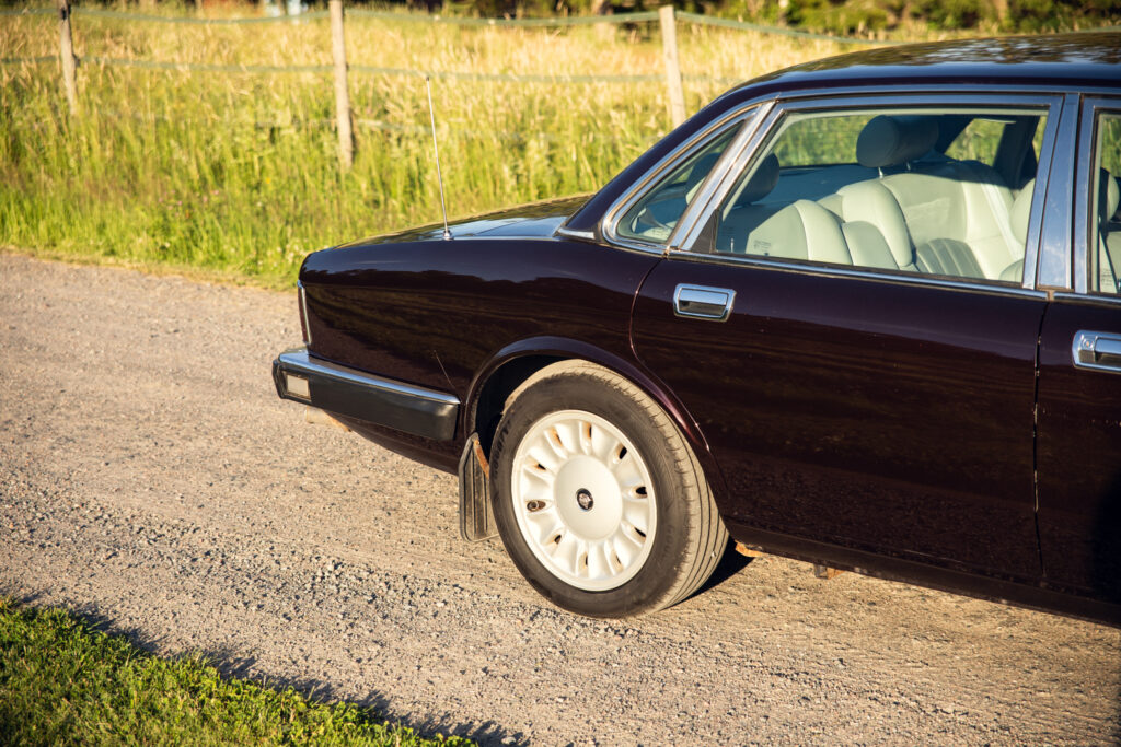 Dark luxury sedan parked on rural gravel road