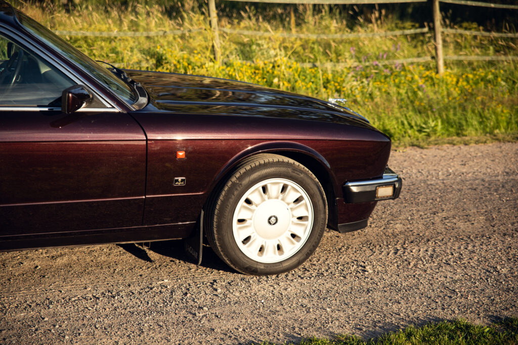 Classic maroon car front wheel on gravel