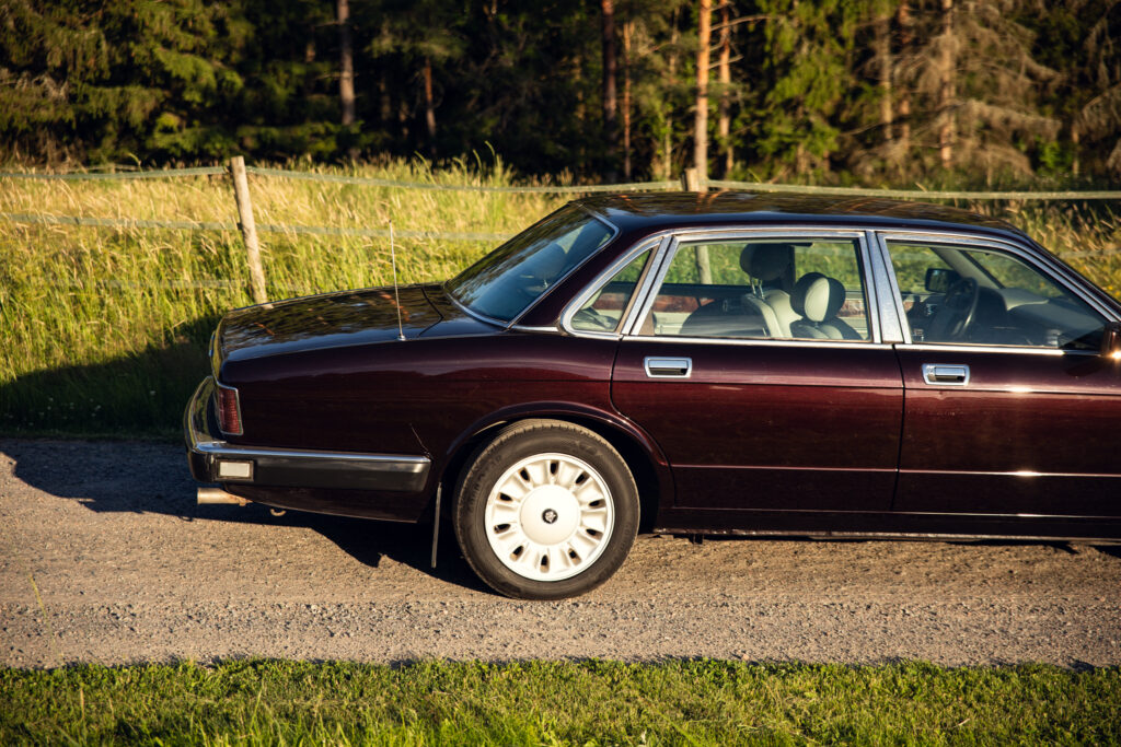 Vintage maroon sedan parked by rural roadside