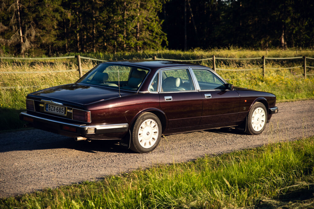 Classic maroon Jaguar sedan on country road