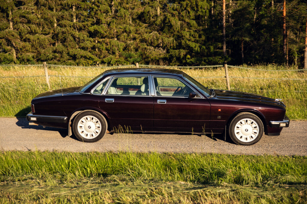 Classic maroon luxury sedan parked on country road