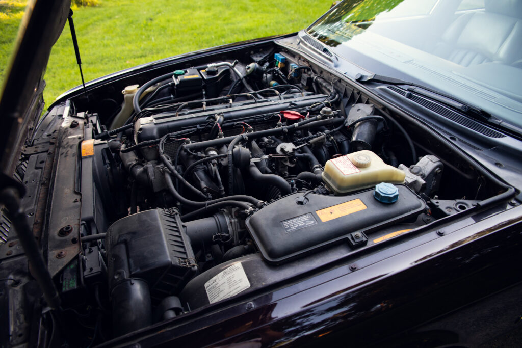 Car engine bay under open hood outdoors
