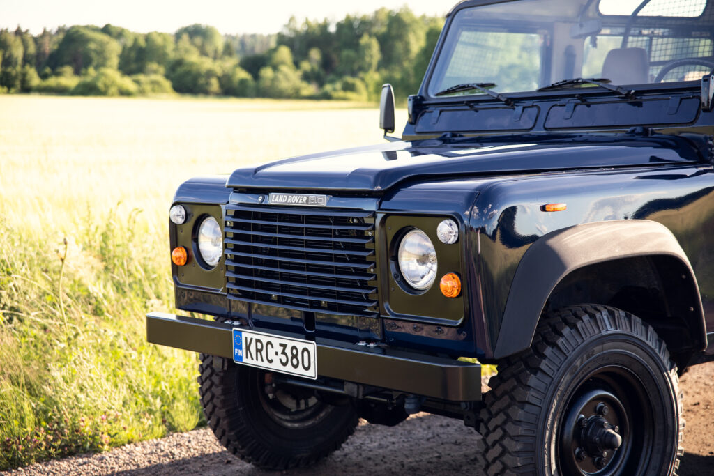 Black Land Rover Defender parked by countryside field