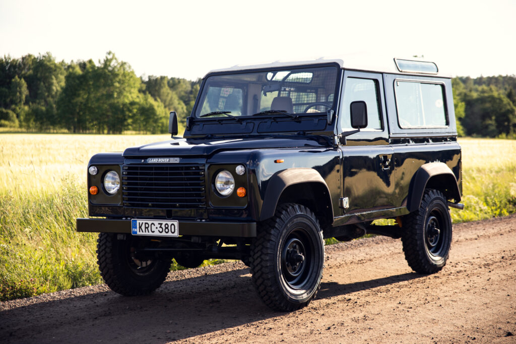 Black Land Rover Defender on rural dirt road