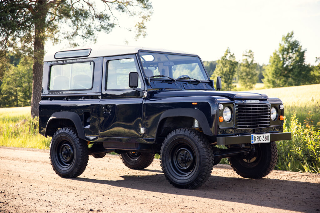 Black classic Land Rover Defender on dirt road