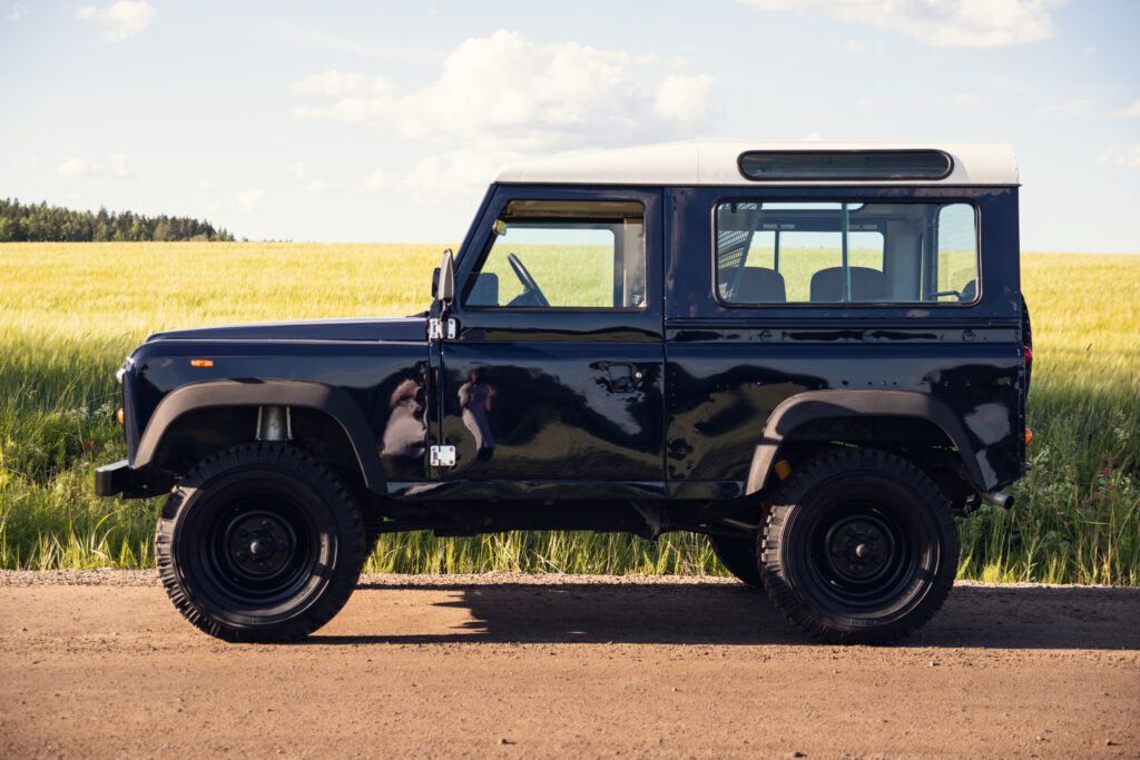 Black vintage SUV parked beside rural field