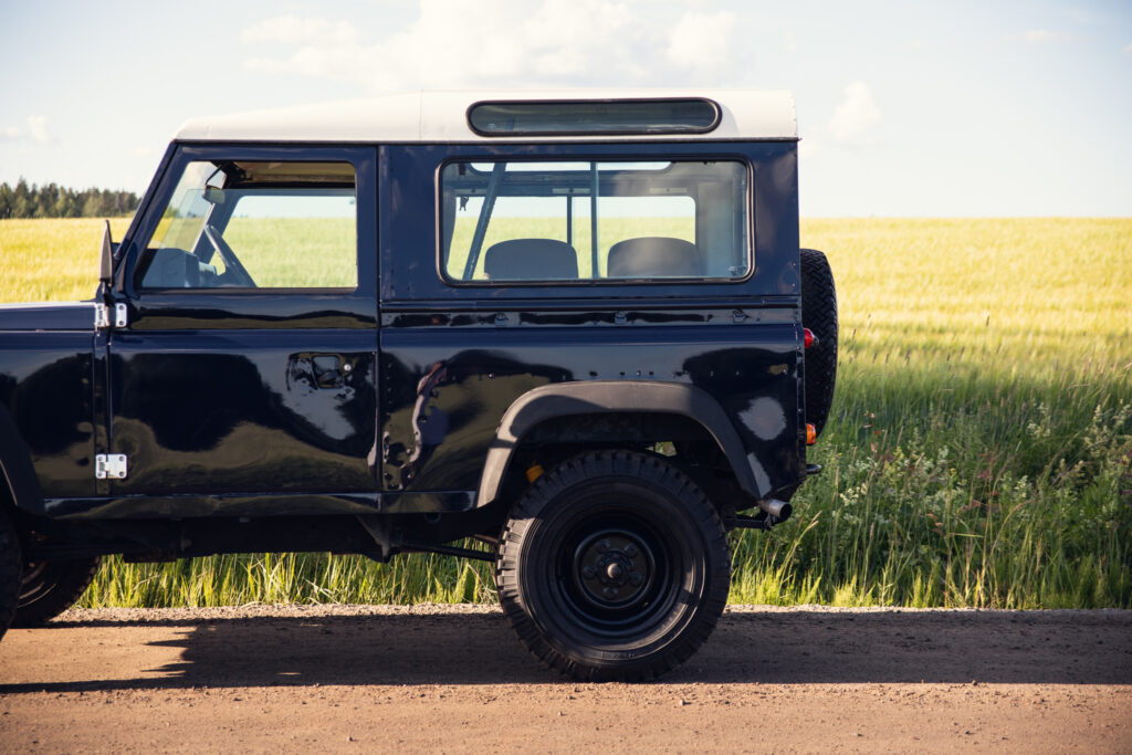 Black vintage SUV parked beside grassy field
