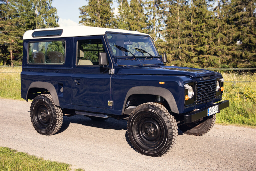 Blue classic Land Rover Defender on rural road