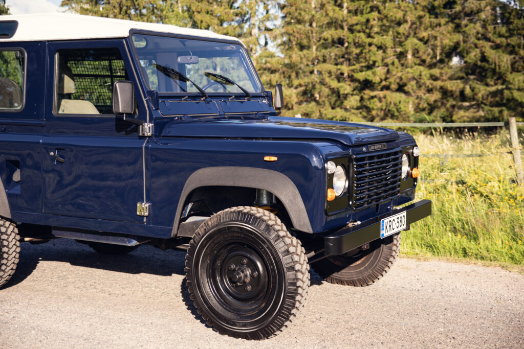 Blue Land Rover Defender parked on rural road