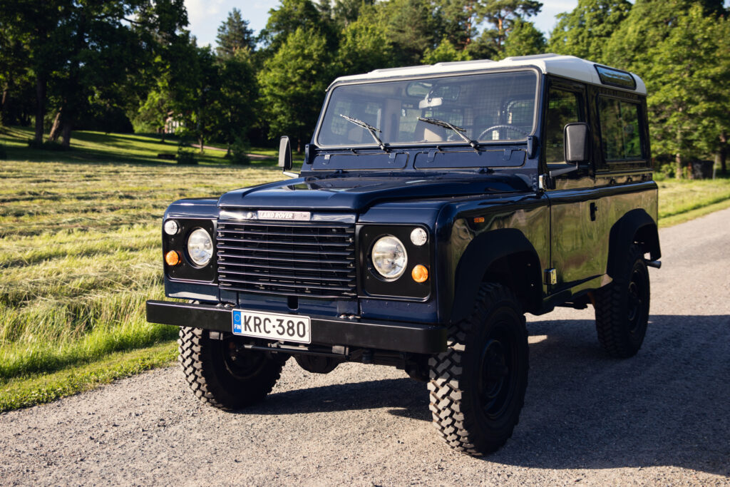 Classic dark blue Land Rover Defender on gravel road