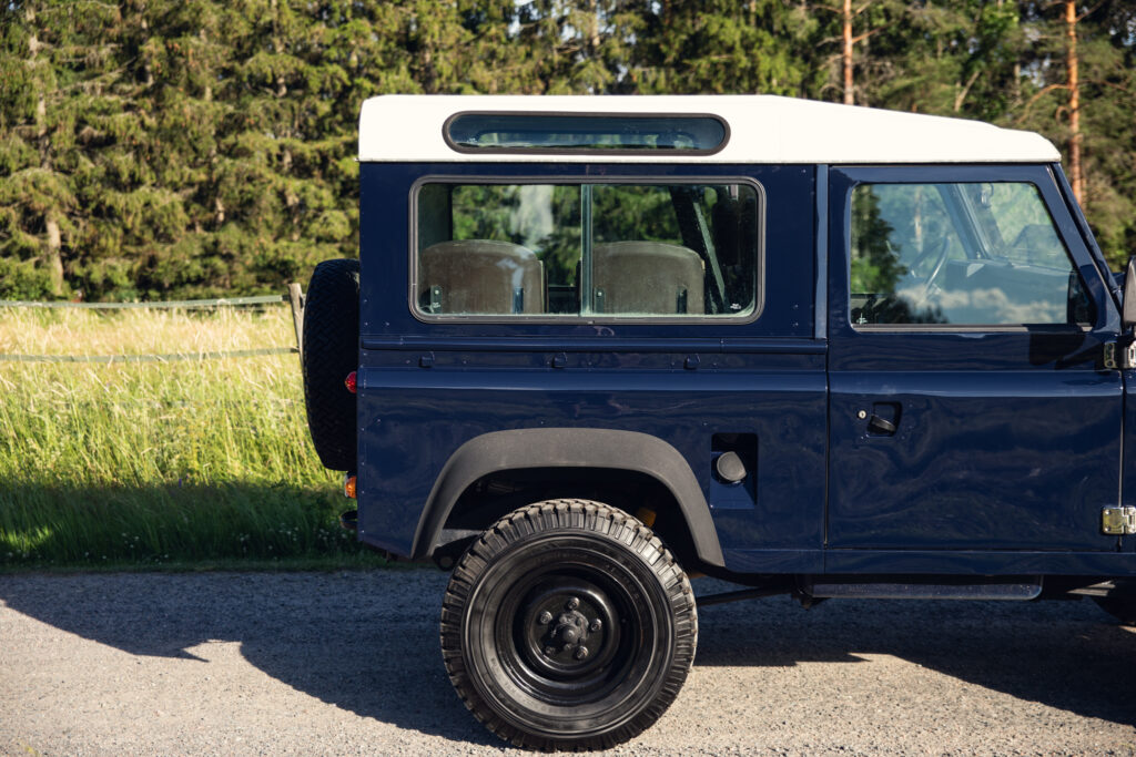 Blue vintage SUV parked beside grassy field