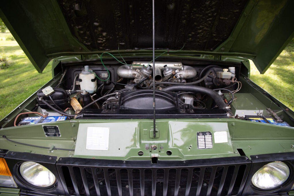 Open hood revealing engine of green SUV
