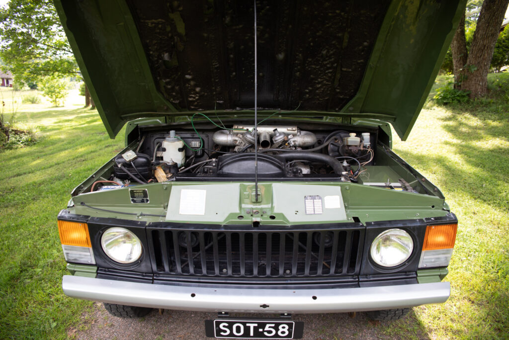 Open hood of vintage green SUV engine
