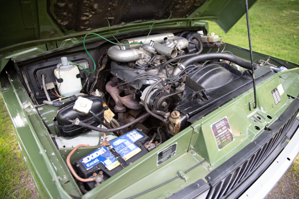 Open hood showing classic green vehicle engine bay