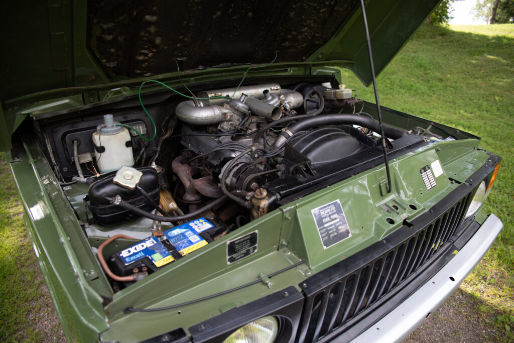 Open hood showing engine of green off-road vehicle